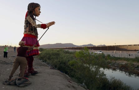 Little Amal walks along the banks of the Rio Grande, in front of the United States border wall, in Chihuahua state, Mexico, on 26 October 26.