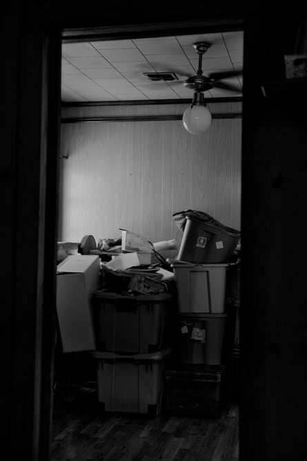 Lesley’s belongings fill stacked storage bins and boxes in a cluttered room, seen through a doorway immersive-3-up