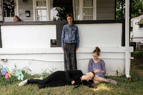 Triplet sisters Alicia, Allison and Amber pose outside, one standing on a wall, two resting on grass