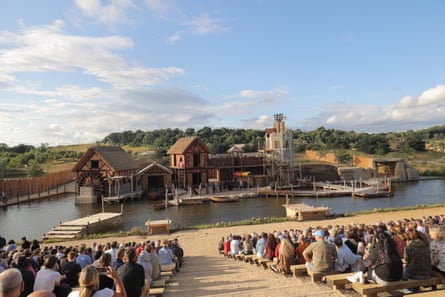 People watching a recreated medieval style village with a moat around it