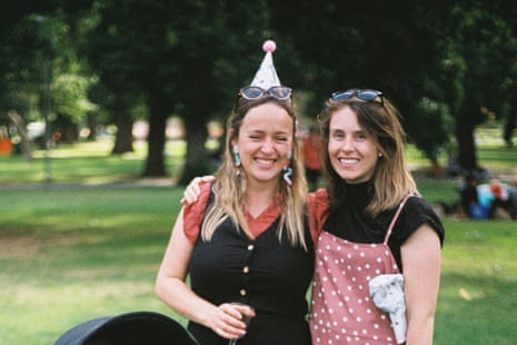 Two women smiling and posing for a photograph in a park.