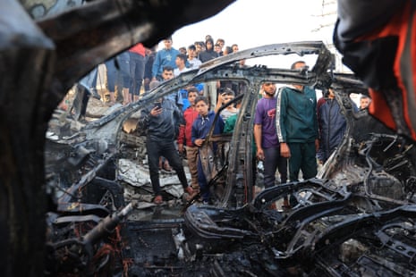 Palestinians inspect a vehicle targeted by an Israeli strike in Maghazi camp for Palestinian refugees in the central Gaza Strip