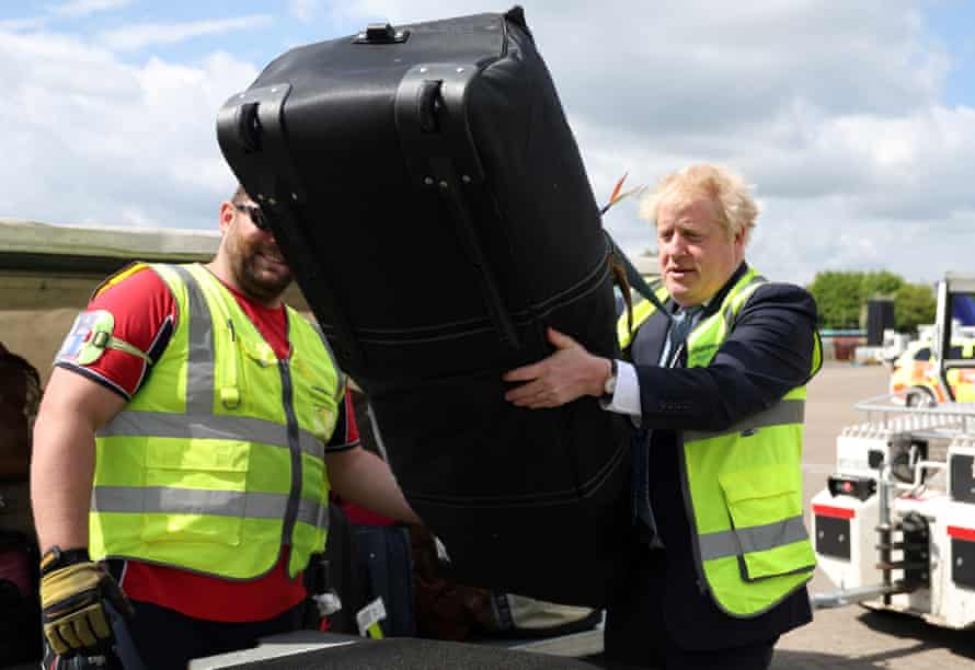 Boris Johnson loading bags on a conveyor belt during a visit to Southampton airport today.