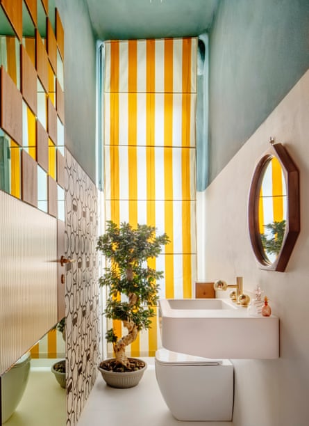 The bathroom with a white suite, mirrored tiles and a yellow and white vertical striped floor-to-ceiling blind