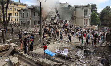 People stand in and around a damaged building