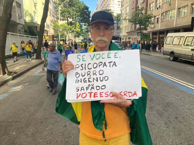 Marcelo Cunha, a 85-year-old Bolsonaro supporter, holds a placard that reads: “If you’re a psychopath, thick, naive or shameless, vote for the left.”