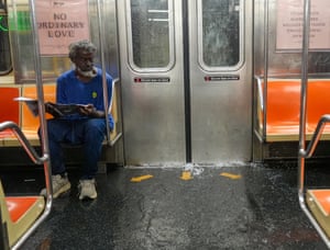 A man sits on a subway train as water seeps into the carriage under the doors, flooding the floor