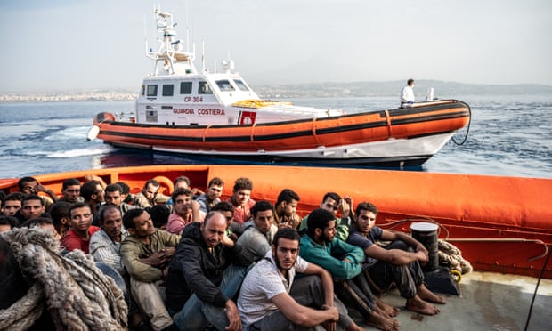 Migrants onboard a vessel escorted by an Italian coastguard patrol boat in Catania, Sicily, in June