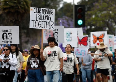 a person holds a sign that reads ‘our families belong together’