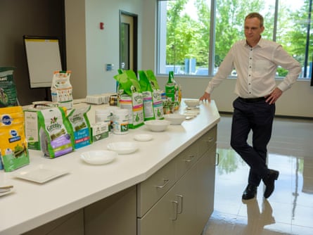 A business-casual man at a counter loaded with pet-care products.