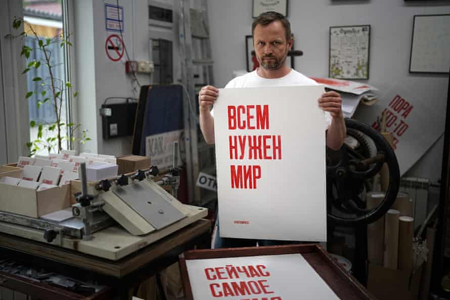 Sergei Besov holding a poster that reads ‘Everyone needs peace’ in his workshop in Moscow on Tuesday 5 July.