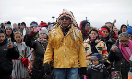 Chief Arvol Looking Horse in a yellow jacket and Indigenous headgear at the front of a group of people.
