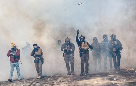 A federal agent lobs a teargas canister towards protesters in Minneapolis on 24 January.