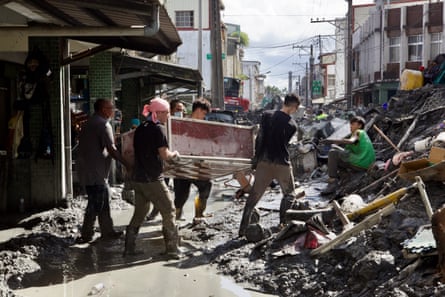 Volunteers carry out damaged furniture into the street to await collection.
