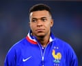 Kylian Mbappe in a blue France jersey looks to the side before a match