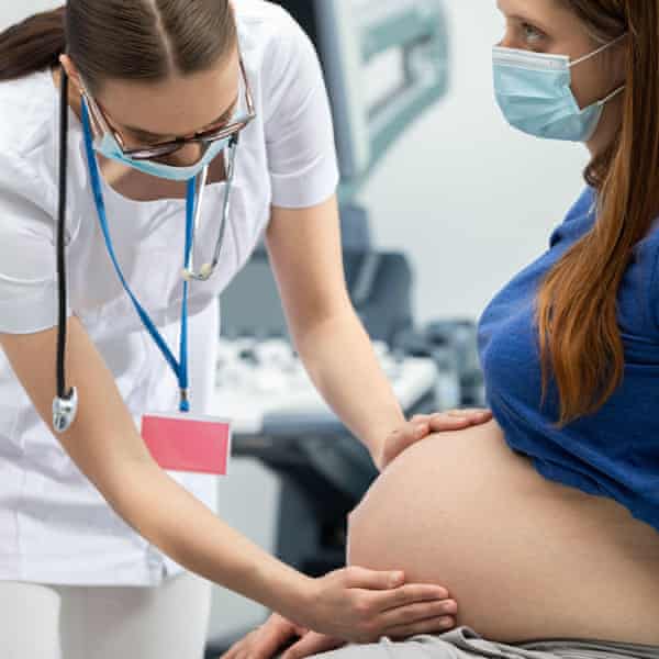 a female medic examining a pregnant woman's abdomen