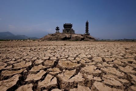 Cracked earth where there is usually a lake, during a drought in Jiangxi province, China, with pagodas in the distance on Louxingdun Island that are usually partially submerged
