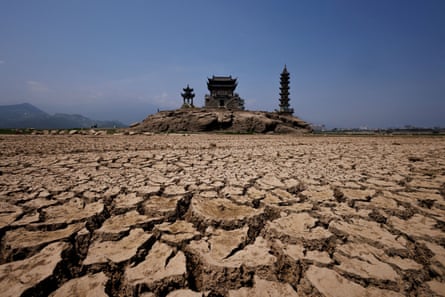 Cracked earth where there is usually a lake, during a drought in Jiangxi province, China, with pagodas in the distance on Louxingdun Island that are usually partially submerged