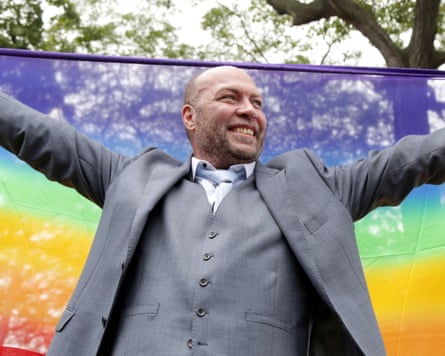 Jason Jones holds a rainbow flag behind him