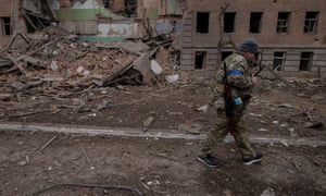 A Ukrainian service member walks past a destroyed building in the town of Okhtyrka in the Sumy region.