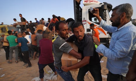 Palestinian people carry boxes of humanitarian aid in the central Gaza Strip.