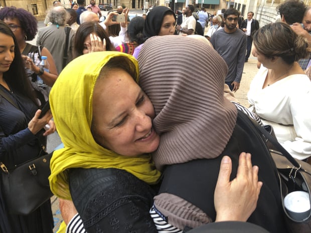Two women wearing headscarves embrace in a crowd.