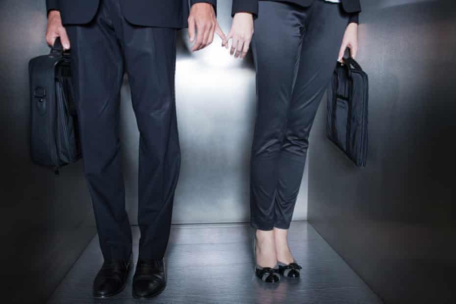 Colleagues holding hands surreptitiously in a lift