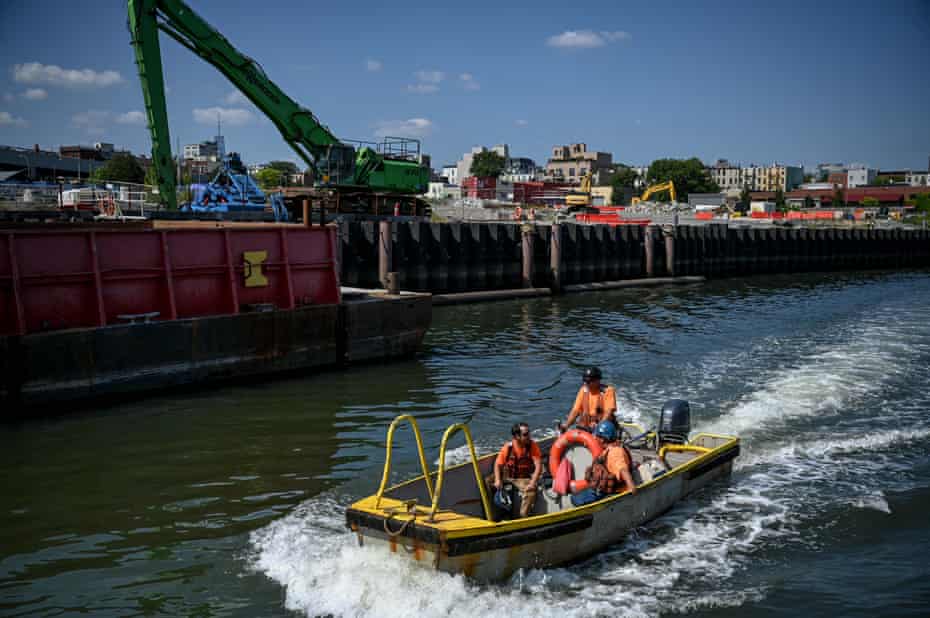 Workers ride down the Gowanus Canal in front of the former Citizens manufactured gas plant in Brooklyn.