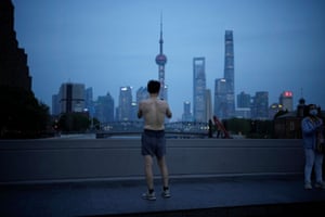 A man takes a photo on a bridge near the Bund in Shanghai