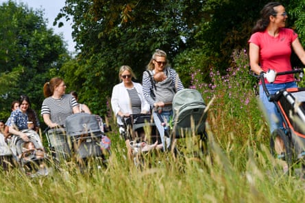 A trail of mothers with pushchairs in a Blaze Trails group walk along long grass