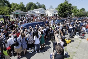 The hearse passes outside his childhood home where mourners wait to pay their respects