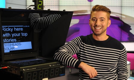Ricky Boleto in a black and white striped t-shirt next to a screen in a TV studio