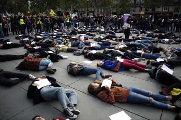女性は、パリでの抗議中に地面に横たわっているときに、パートナーによって殺された女性の名前のプラカードを保持し