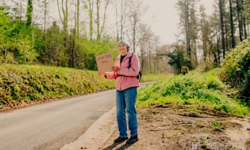 Hilary Bradt holds out a polite sign on a road near Colyton, Devon.