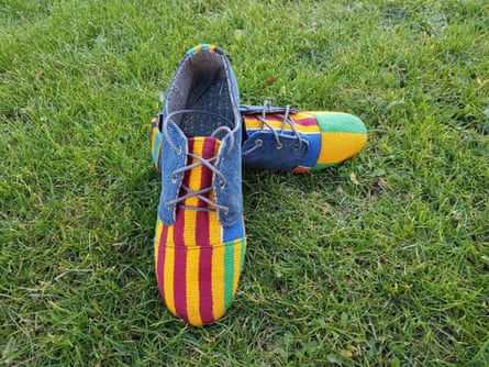 A pair of lace-up shoes with denim tops and red and yellow striped toecaps