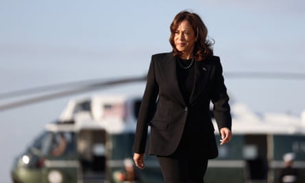 Kamala Harris, wearing a black pantsuit, walks away from a helicopter