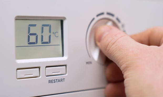 A homeowner turning down the temperature of a gas boiler