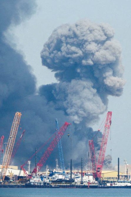 Smoke billlowing behind cranes at what appears to be a port