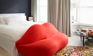 A dazzling scarlet sofa and Missoni rug in the main bedroom, set off by dark paint and and neutral curtains.