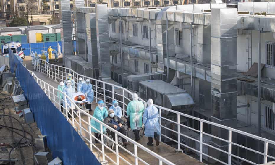 Medical workers in protective suits help transfer the first group of coronavirus patients into the newly completed Huoshenshan temporary field hospital in Wuhan, China.
