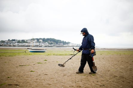 A man with a metal detector on a beach