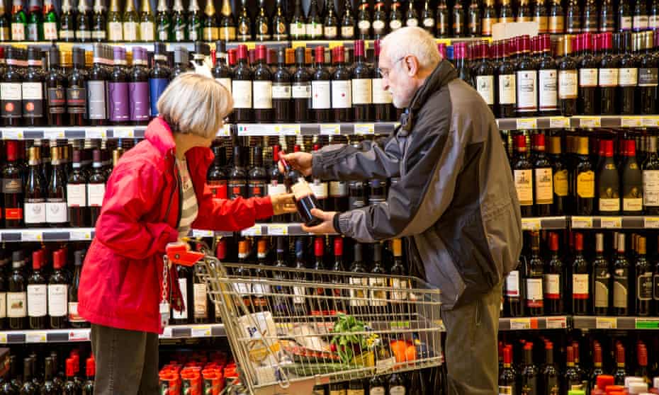 shoppers discuss which wine to buy in a supermarket