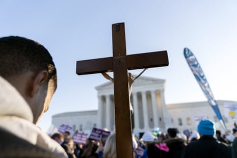 An anti-abortion protester holding a cross in front of the U.S. Supreme Court as it hears arguments in December 2021, in a case seeking to overturn Roe v Wade. (AP Photo/Jose Luis Magana)
