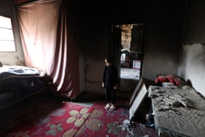 A young girl stands inside a damaged house after it was set on fire by Israeli settlers in Sinjel near the West Bank city of Ramallah