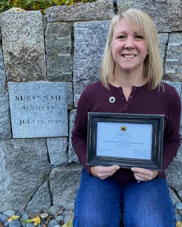 Lindsay Perodeau astatine  the Proctor’s Ledge memorial successful  Salem, dedicated to her ancestor, Susannah Martin. She is holding her ‘Daughter of a Witch’ certificate.