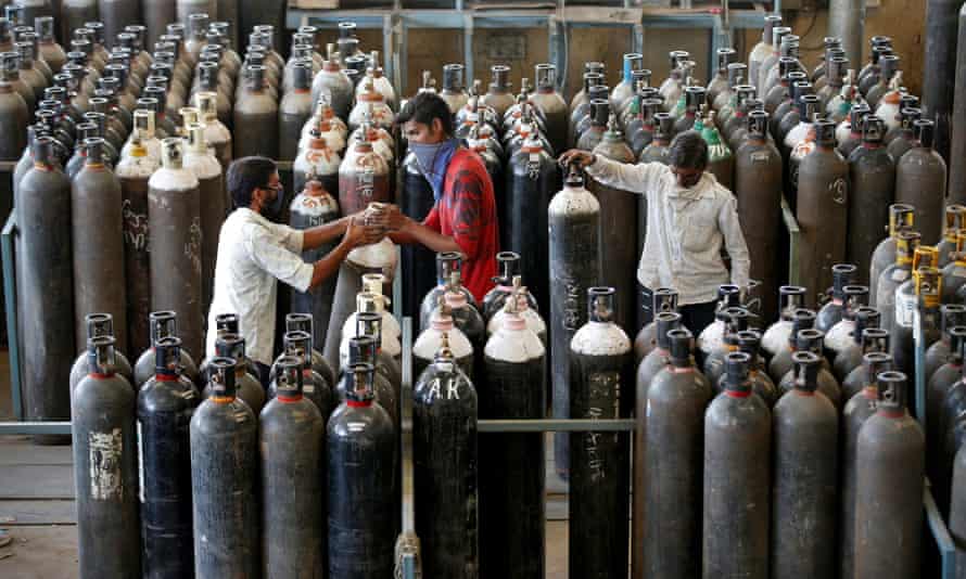 People carry oxygen cylinders after refilling them in a factory in Ahmedabad. India recorded 352,000 Covid cases on Monday.