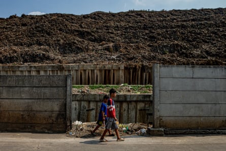 Children walk past towering mounds of waste
