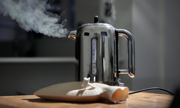 A domestic electric kettle emits steam and vapour next to a hot water bottle