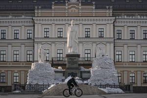 A man rides a bicycle backdropped by a statue of Grand Princess Olga of Kyiv, in the process of being covered in sandbags to avoid damage from potential shelling, in Kyiv, Ukraine.