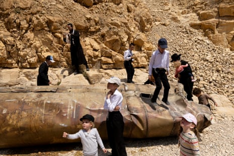 Children play with missile debris while a man takes photos of the missile shell